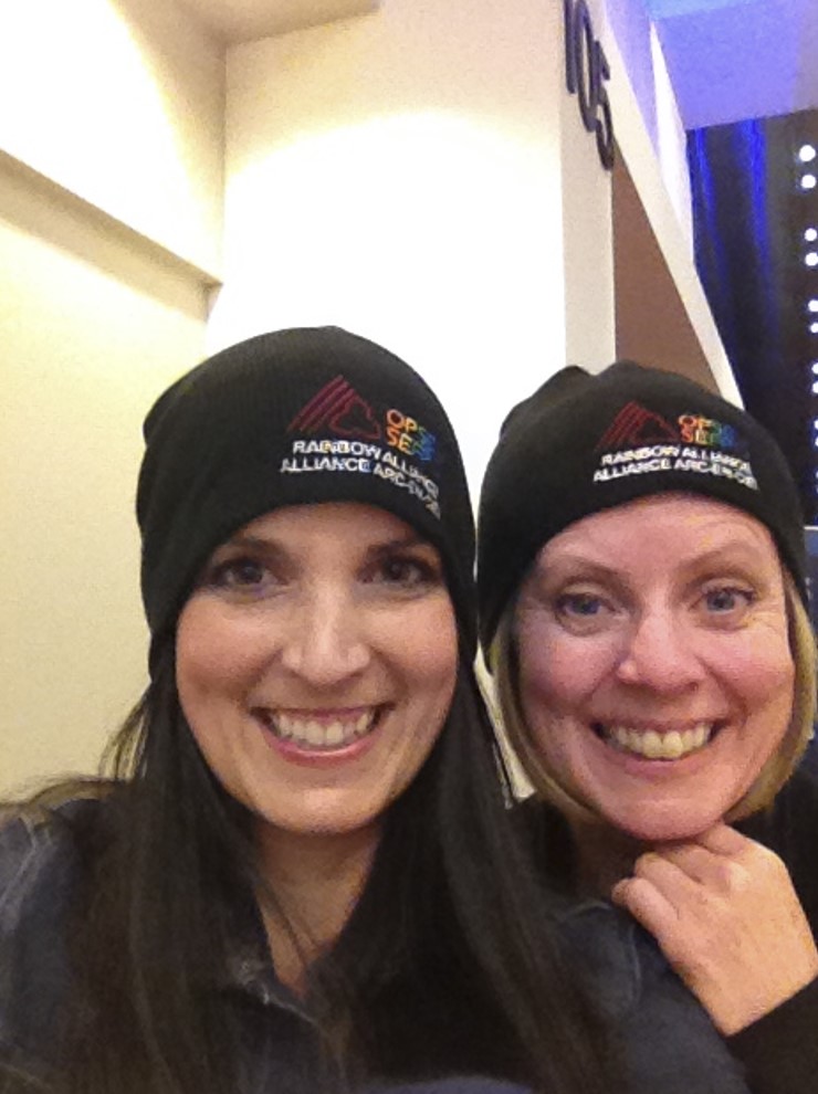 A selfie of two people each wearing a toque reading "Rainbow Alliance."