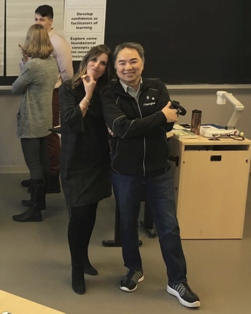 Two people stand together in a classroom. 