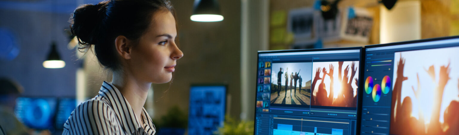 A digital content creators sitting at a desk with coffee and two monitors, editing a video using editing software