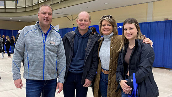 Paige Schlorff standing with her parents Tracey and Terry and Georgian College President and CEO Kevin Weaver in a gym, smiling, while at Open House