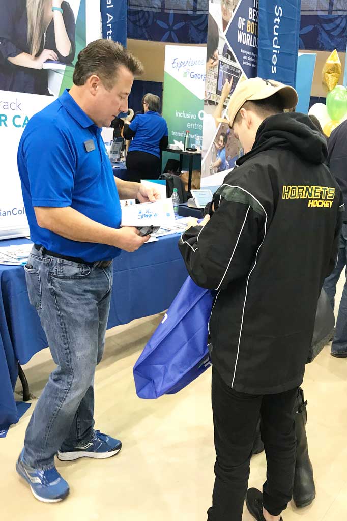 Stephen from Georgian's recruitment team showing a prospective student some marketing materials at an in-person event
