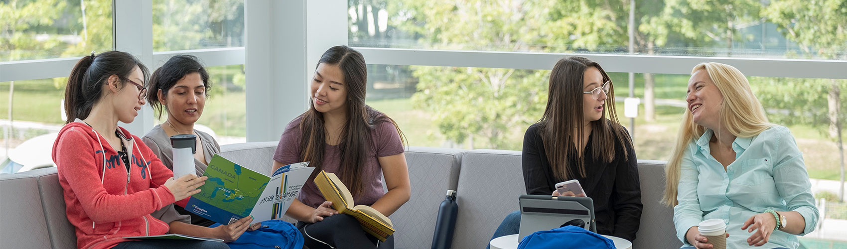 five female students sitting and chatting together on campus