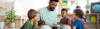 An Early Childhood Educator (ECE) reading to a group of young children in a daycare centre