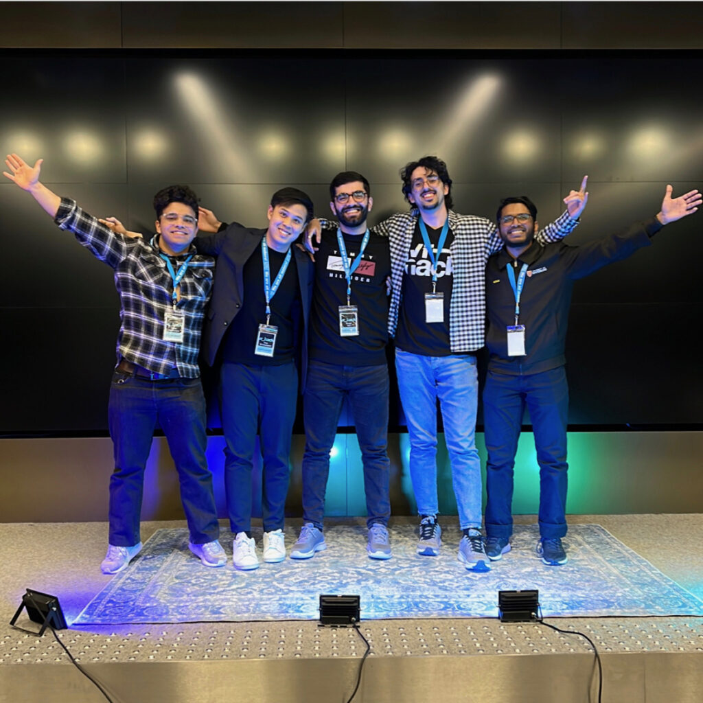 Five smiling males standing on a stage.