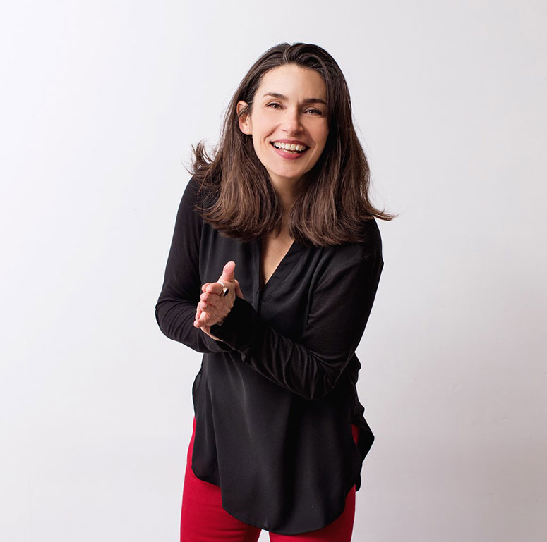 A smiling woman (Jan Bailey) wearing a black shirt and red pants. She has long black hair.