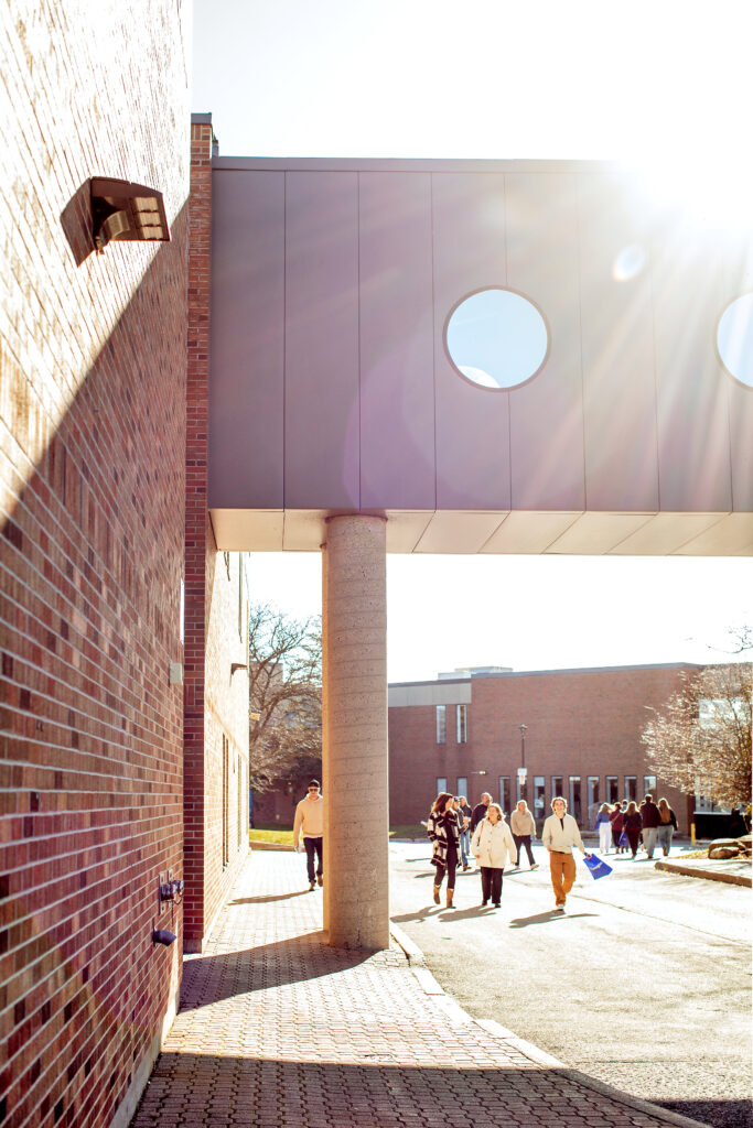 People walk around a college campus outside. 