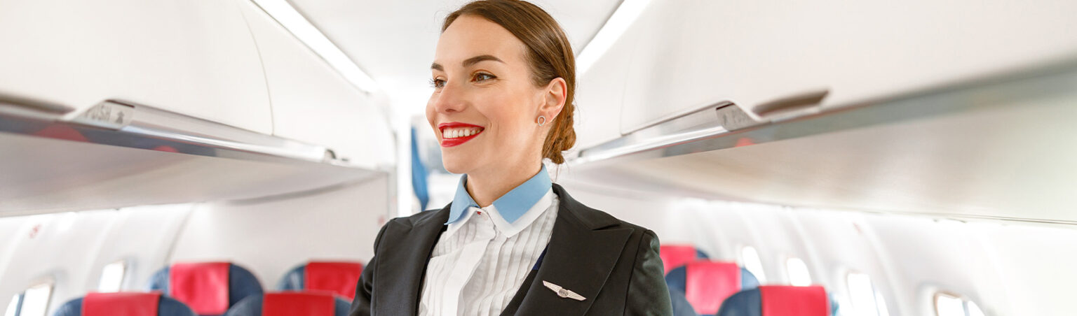 A flight attendant in uniform on a airplane checking the cabin is ready.