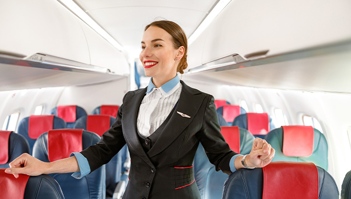 A flight attendant in uniform on a airplane checking the cabin is ready.