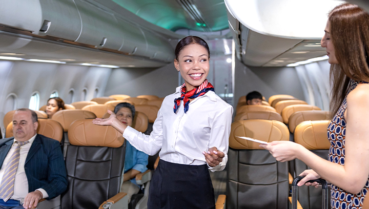 A flight attendant in uniform on a airplane checking checking in a passenger