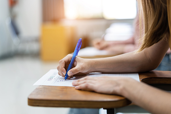 close up hand of female college student writing an exam