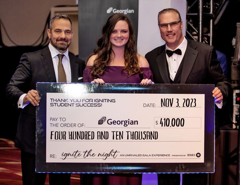 Three people dressed formally hold up an oversized cheque for $410,000.