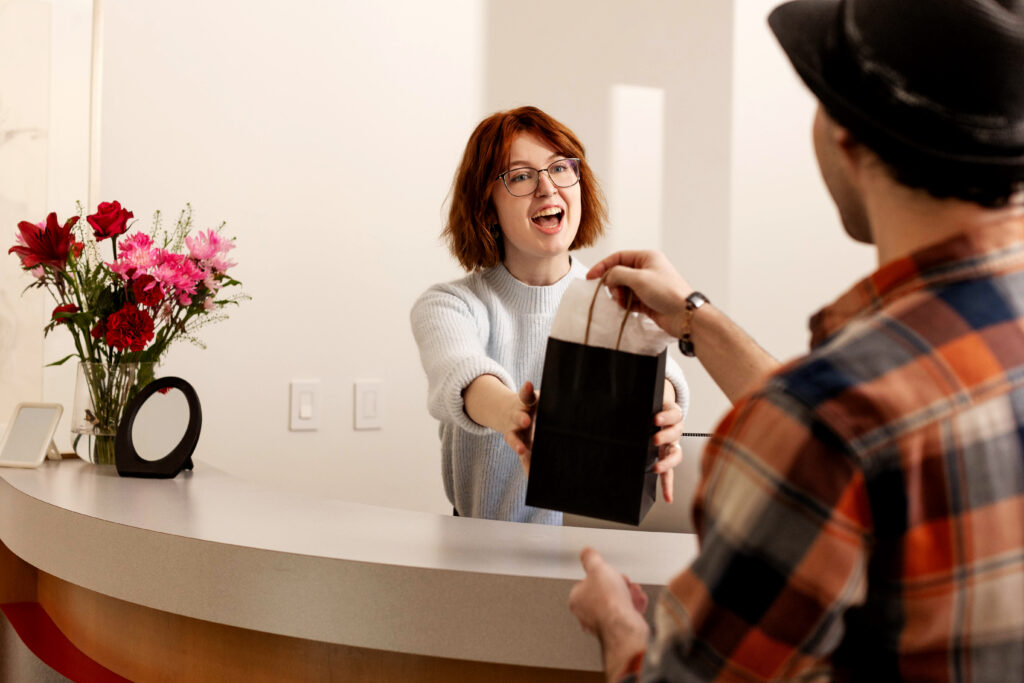 A woman helps someone check out at the cash desk