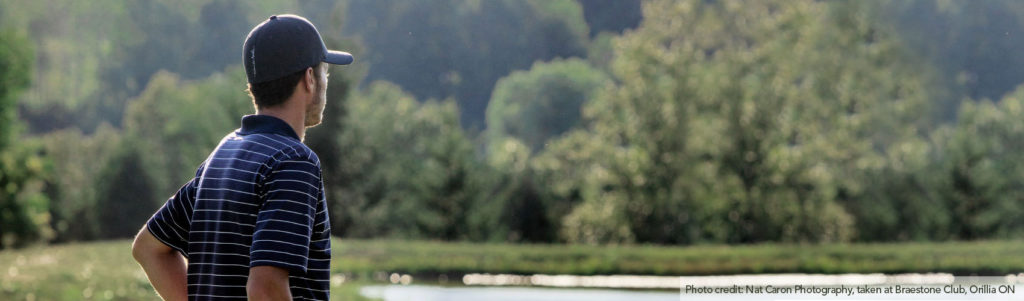 Golfer wearing a gray ballcap and navy blue and white striped shirt, looking out at Braestone Club in Orillia, Ontario