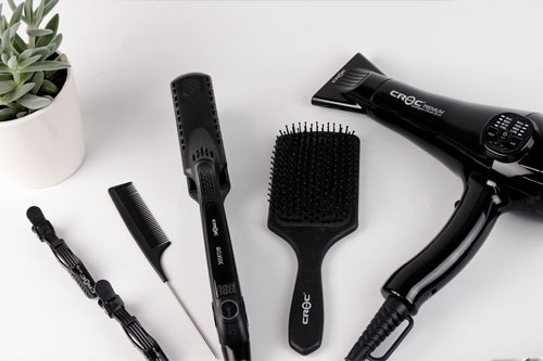 Black hairdressing tools on a white background with succulent in the background