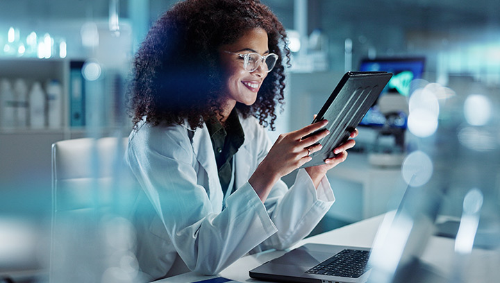 A woman in a lab coat studies a tablet. Blue bubble with text "Online"