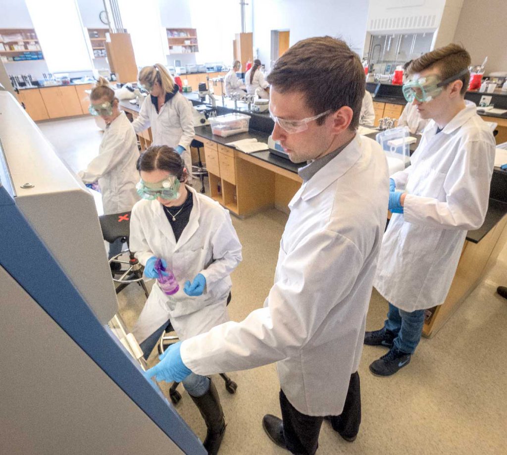 a group of female and male students in lab coats and safety glasses performing a culture test in the chemistry laboratory at Georgian College's Barrie Campus