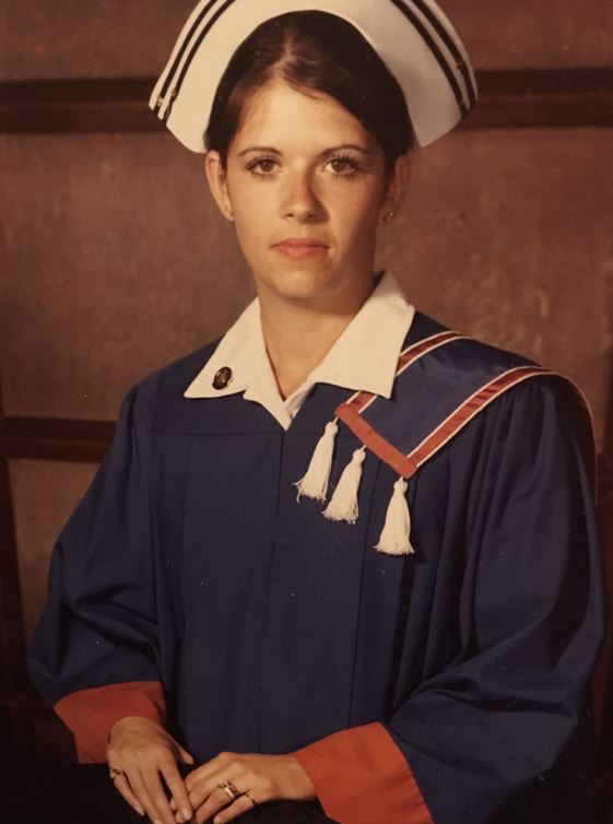 A graduation photo of a person wearing a blue robe and nurse's hat.