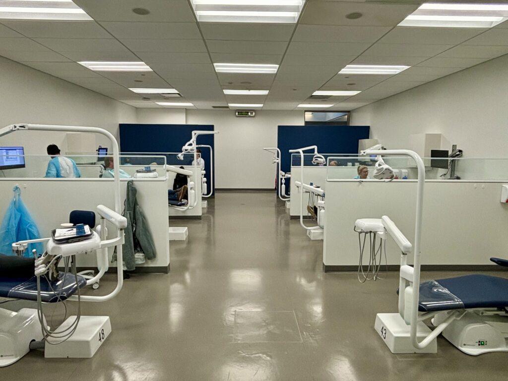 A room sectioned into six areas, each with a dental chair and equipment. 