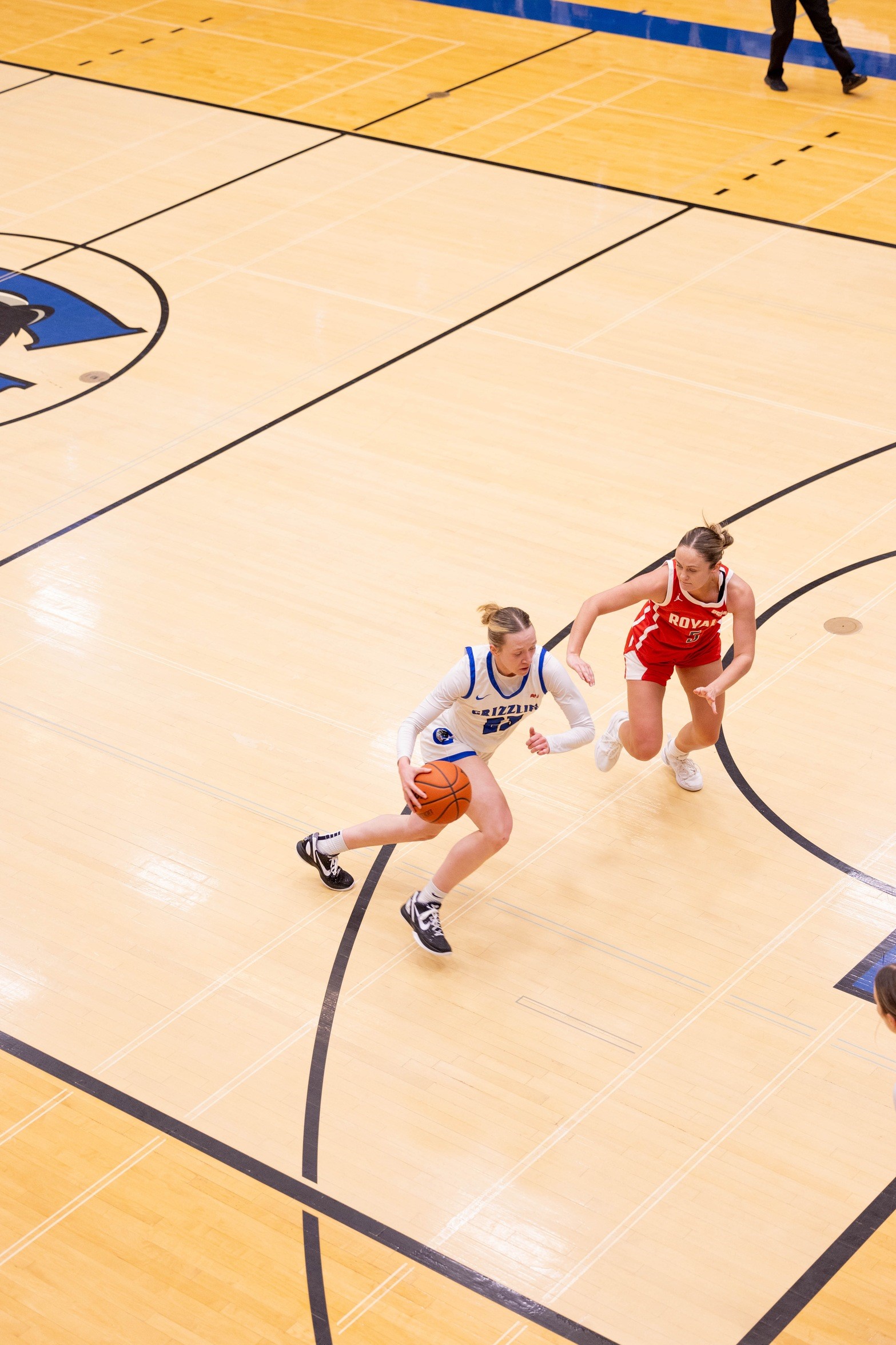 Two people on opposite teams play basketball on a court. 