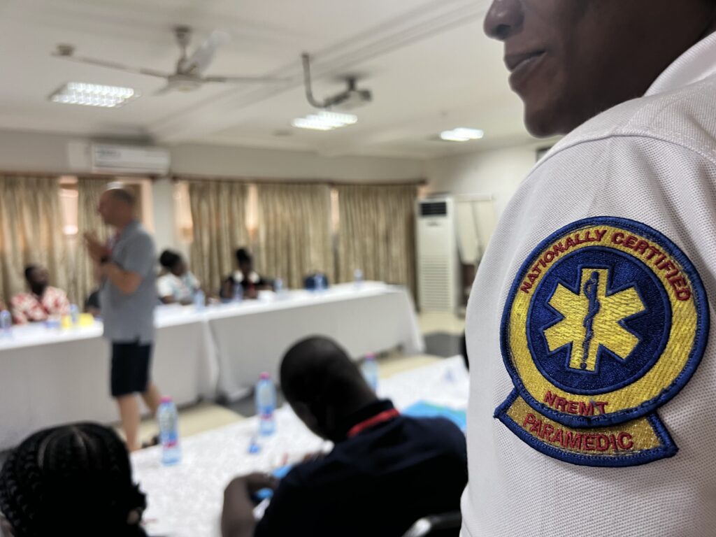 A closeup of a person wearing a white paramedic uniform with a patch reading: Nationally certified paramedic. 