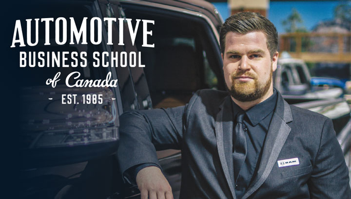 Automotive student with slicked back hair and a beard wearing a black suit and tie while leaning against a black Dodge Ram truck