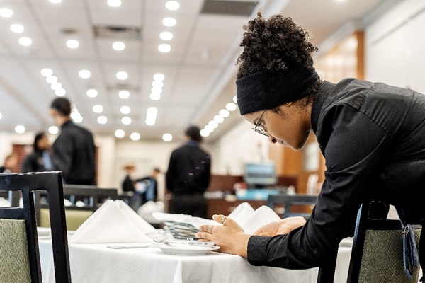 Student in Georgian Dining Room prepping a table