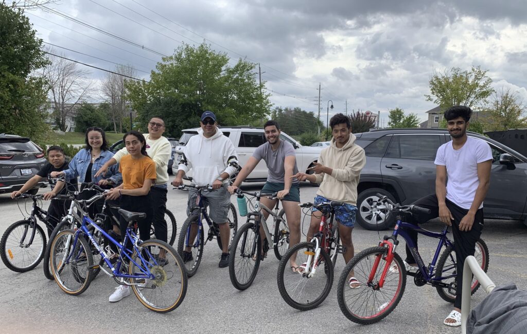 Eight adults stand outside in a parking lot next to bikes. 