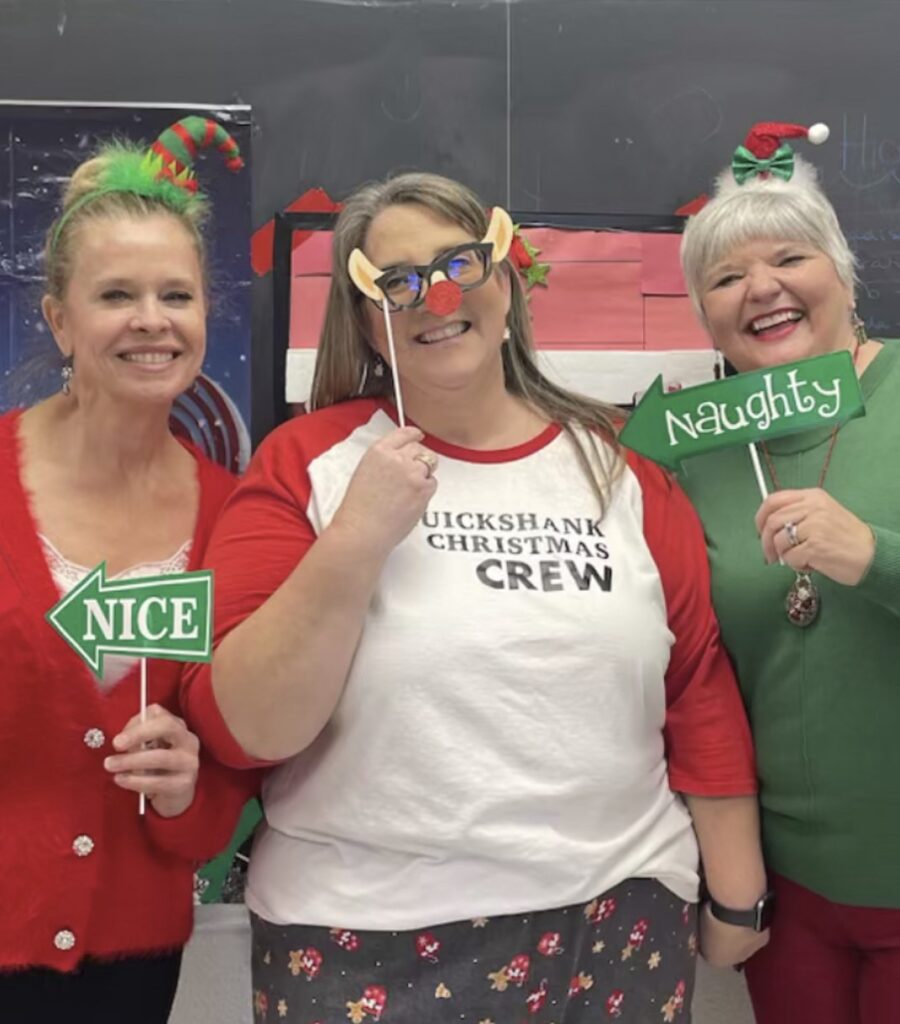 Three people wearing red, green and white and Christmas accessories hold small signs reading "Nice" and "Naughty."