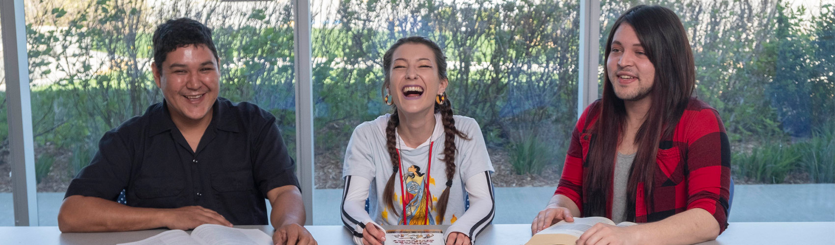 three Indigenous students sitting together at a table with books in front of them