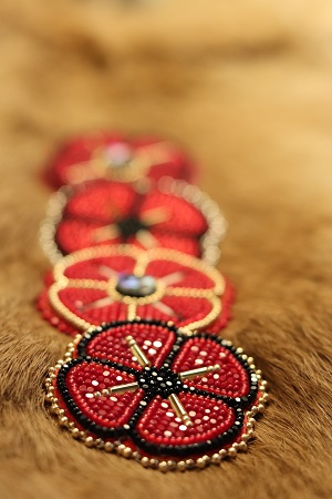 Beaded red and black poppies laying on a brown fur piece.