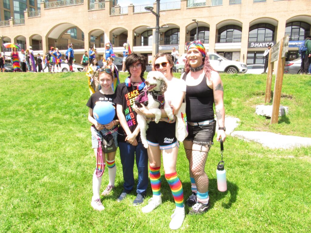 Two adults, two kids and a dog pose for a photo at a Pride event. 
