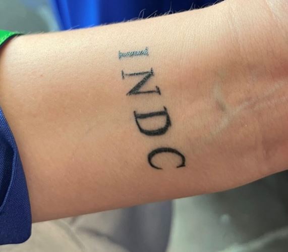 A closeup of a tattoo reading "INDC" on the inside of a person's wrist.