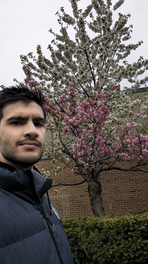Refugee student Luay outside at the Barrie Campus near blossoming tree