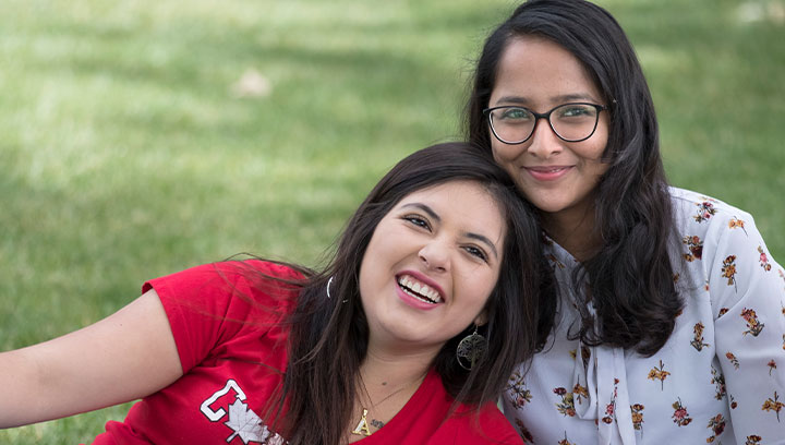 international students smiling while sitting outside on a lawn