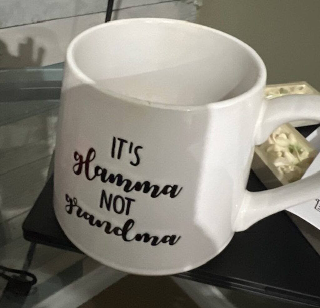 A white mug with black writing that reads: It's glamma not grandma. 