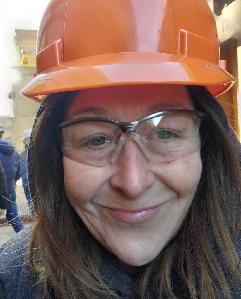A person wearing an orange hard hat and safety glasses.