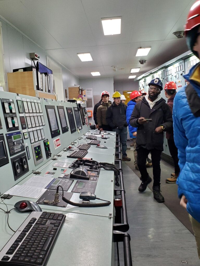 A group of people standing around a control area inside a ship.