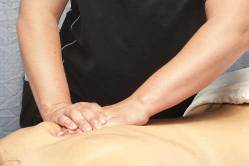 Photo of massage therapist performing massage on a client's back