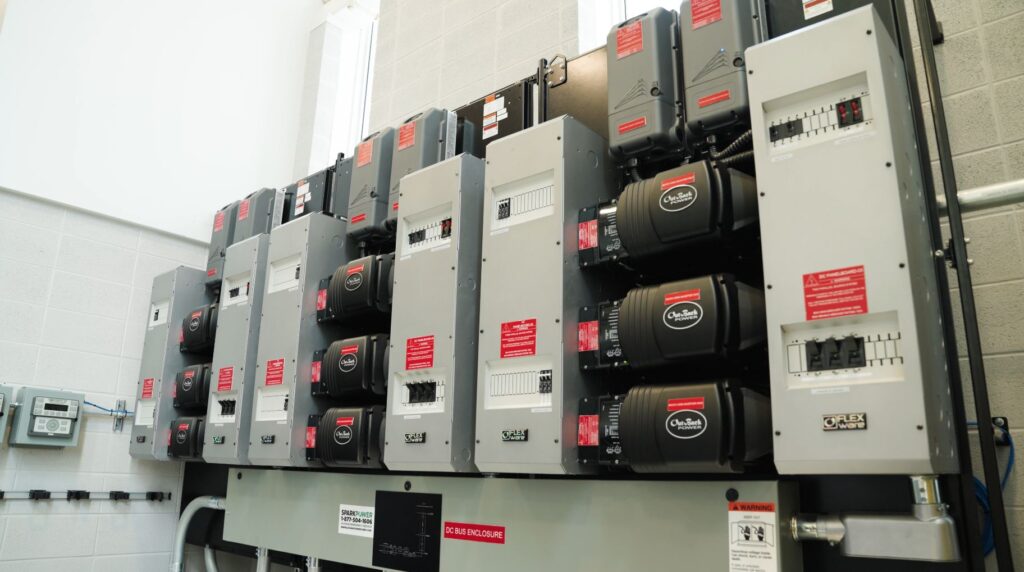 Multiple grey and black boxes with red stickers that make up Georgian's microgrid system.