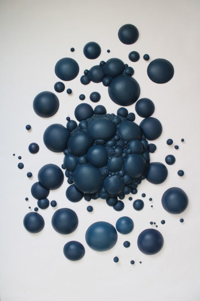 A piece of artwork with various sizes of blue bubbles scattered together.