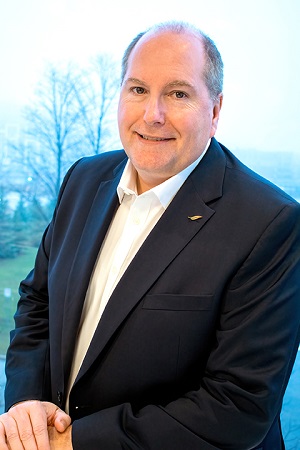 New vice presidents: Vice President, Finance and Corporate Services, David Johnson in black suit jacket, white shirt, stands near window smiling warmly