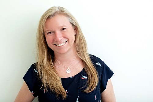New vice presidents: Vice President, Student Success, Suzie Addison-Toor stands against white wall, wearing short-sleeved navy patterned shirt, warm smile, medium-length blonde hair