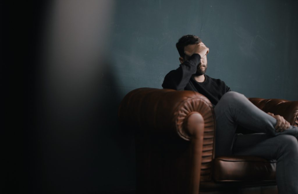 Man sitting on a couch rubbing his head