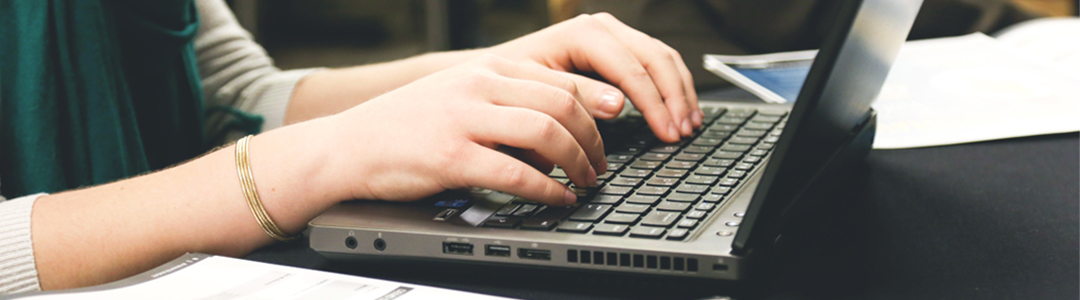 Hands typing on a laptop