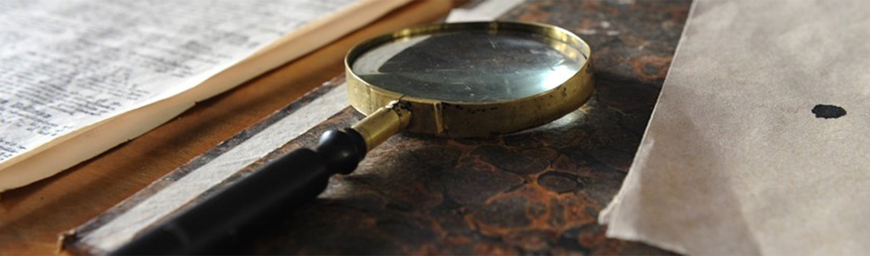 A black and gold magnifying glass resting on a speckled notebook