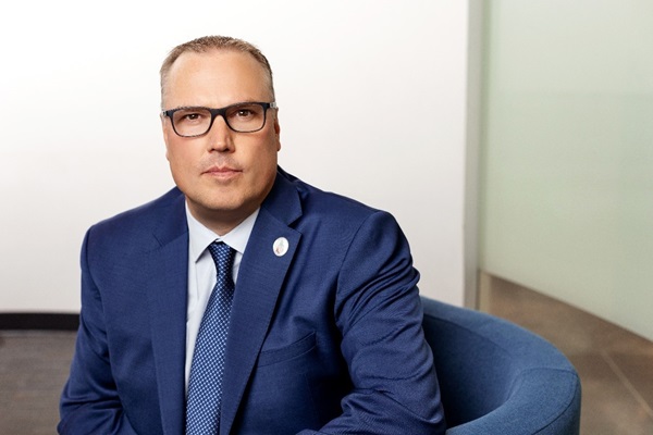 President and CEO Kevin Weaver sitting in blue chair, wearing blue shirt