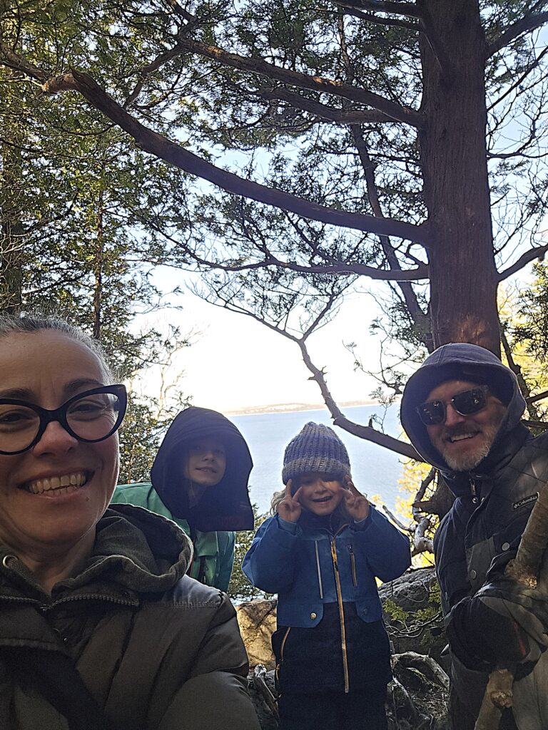 Two adults and two children take a selfie in the woods.