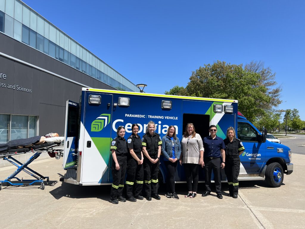 Georgian Paramedic students and faculty stand in front of a new training vehicle at the Barrie Campus.