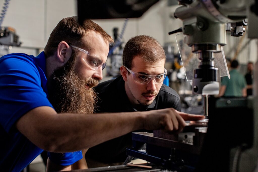 Partnerships drive student learning; faculty and student learn together on an advanced machine in a skilled trades lab