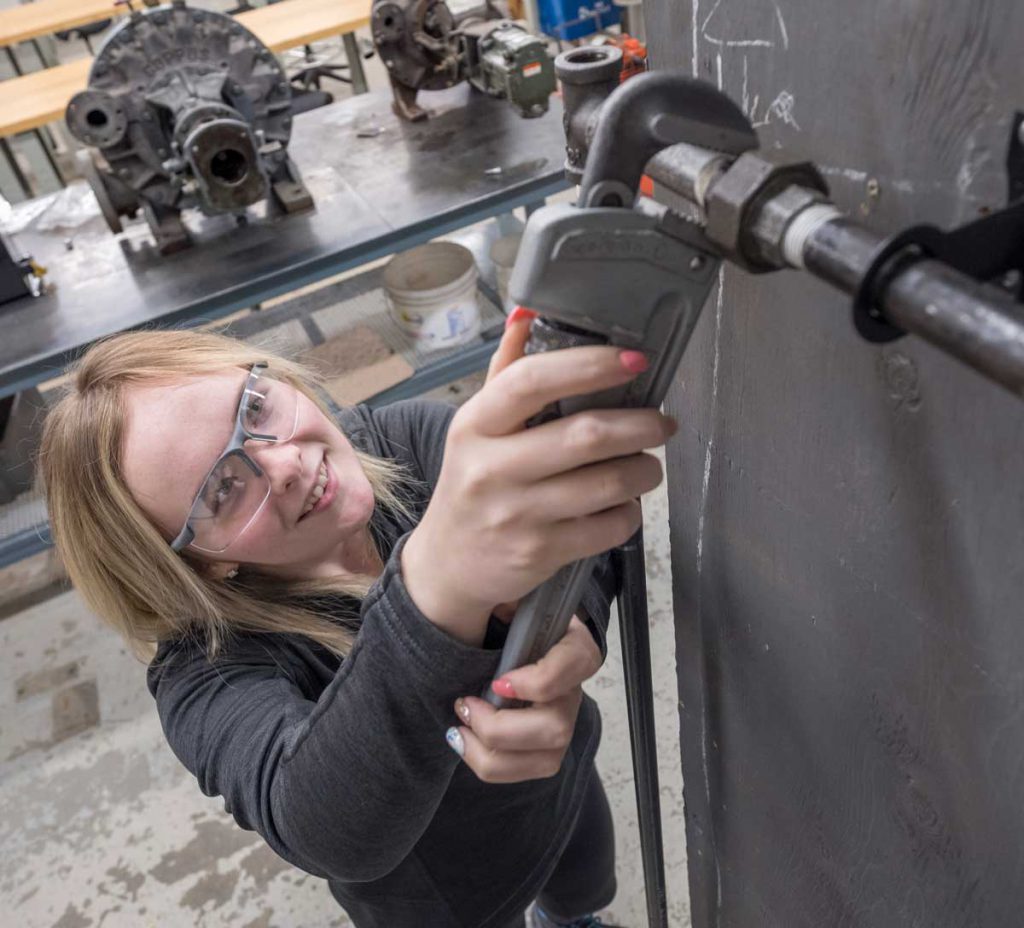 female power engineering technology student at Georgian's Owen Sound campus using a wrench on a piece of machinery